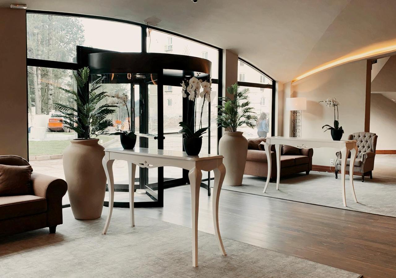 Buona Vitta Gramado Resort & Spa By Gramado Parks Bagian luar foto The photo displays an elegant interior space, likely a hotel or a high-end lobby. In the foreground, there is a stylish table with a curved design, positioned near large glass doors leading outside. Flanking the table are two large planters with lush