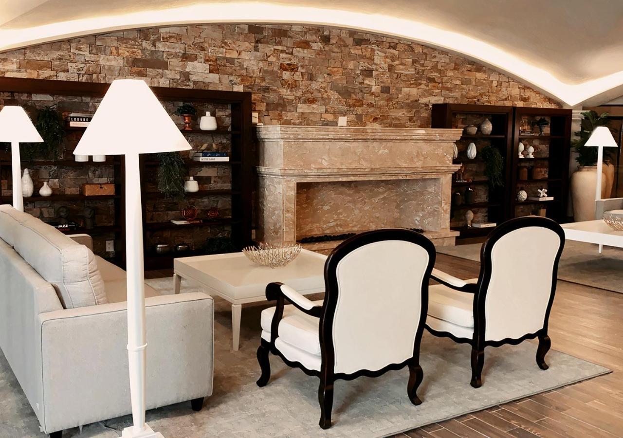 Buona Vitta Gramado Resort & Spa By Gramado Parks Bagian luar foto The photo shows a stylish living room with a modern design. In the center, there is a light-colored sofa and two elegant white armchairs with black wooden frames. A coffee table is placed in front of the sofa. Behind them, there is a large, decorativ