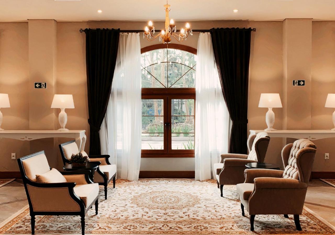 Buona Vitta Gramado Resort & Spa By Gramado Parks Bagian luar foto The photo shows an elegantly styled living room. There are two armchairs and a sofa arranged comfortably around an intricate area rug. Large windows are adorned with sheer white curtains and dark curtains, allowing natural light to fill the space. A 