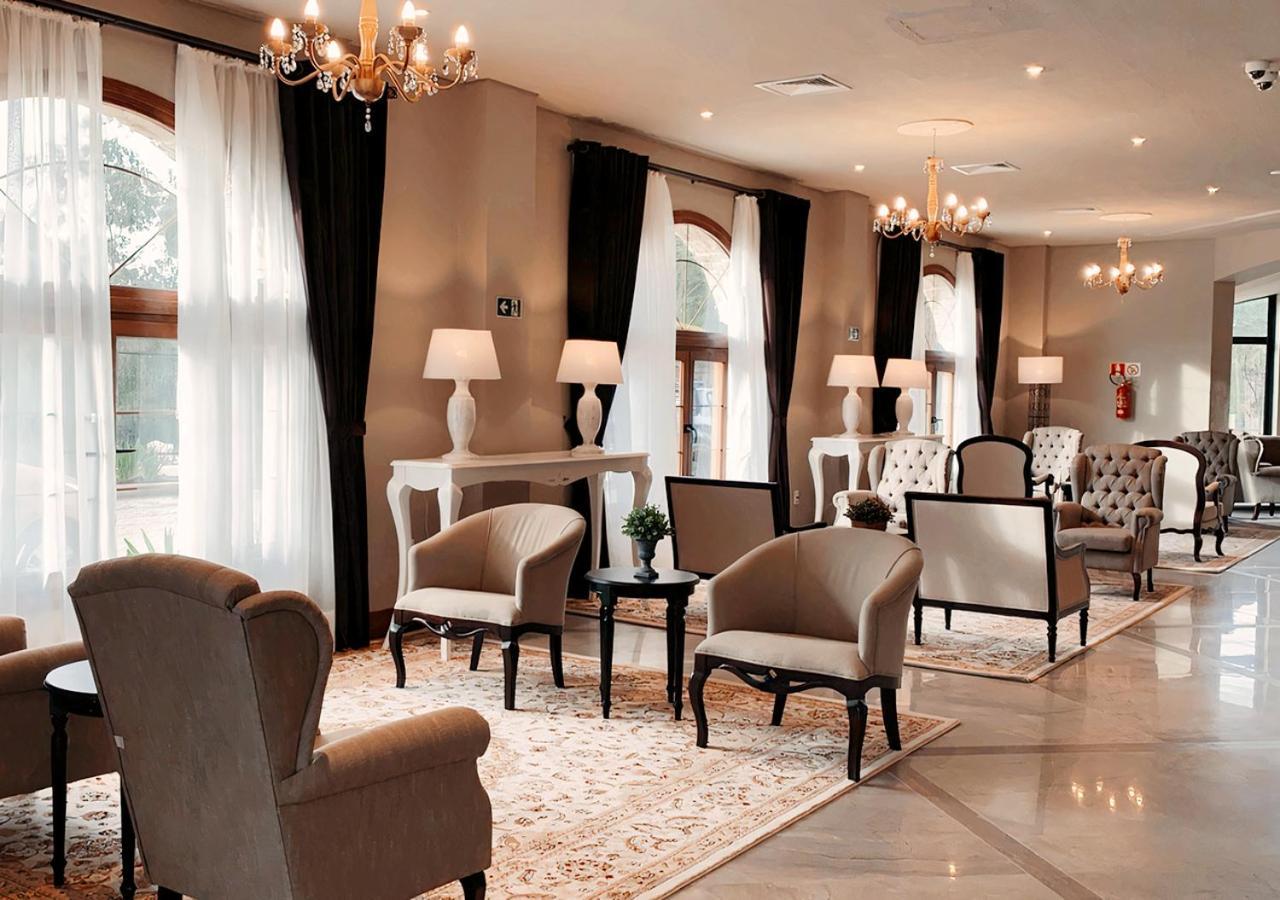 Buona Vitta Gramado Resort & Spa By Gramado Parks Bagian luar foto The photo depicts a stylish and sophisticated lounge area. It features several elegant chairs and sofas, arranged around small tables on a decorative rug. The room is well-lit with natural light coming in through large windows dressed with flowing wh