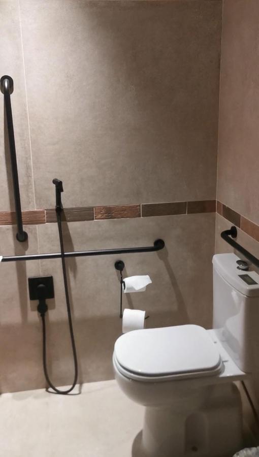 Buona Vitta Gramado Resort & Spa By Gramado Parks Bagian luar foto The photo shows a bathroom equipped with grab bars for accessibility. The walls are tiled in a neutral color, and there is a toilet on the right side of the image. Two rolls of toilet paper are positioned near the toilet, and there are additional ins