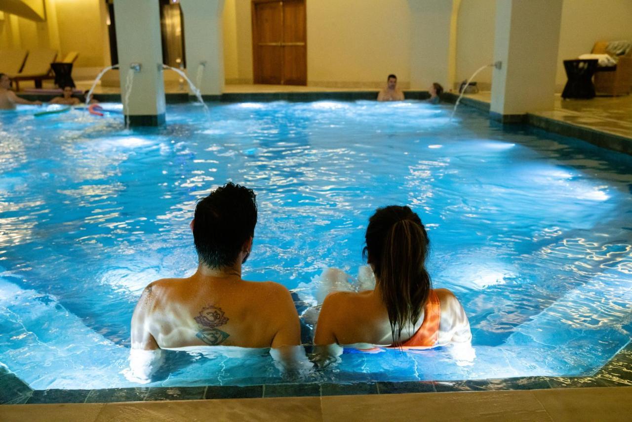 Buona Vitta Gramado Resort & Spa By Gramado Parks Bagian luar foto The photo shows a couple sitting in a swimming pool with gentle lighting. They are facing away from the camera, appearing relaxed and enjoying their time together. The water is illuminated with a soft blue light, creating a serene atmosphere. In the 