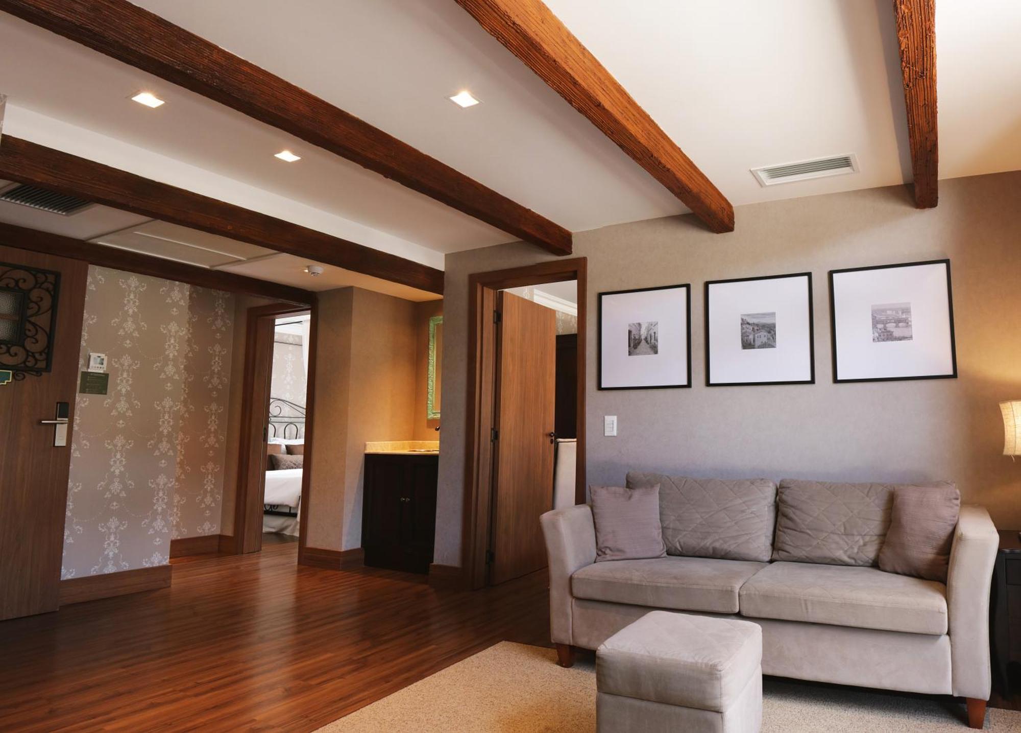 Buona Vitta Gramado Resort & Spa By Gramado Parks Bagian luar foto The photo showcases a modern living space with a cozy and well-lit atmosphere. There are wooden beams visible on the ceiling, adding a rustic touch. The flooring is a warm-toned wood, contributing to the inviting feel of the room. 

On one side, ther