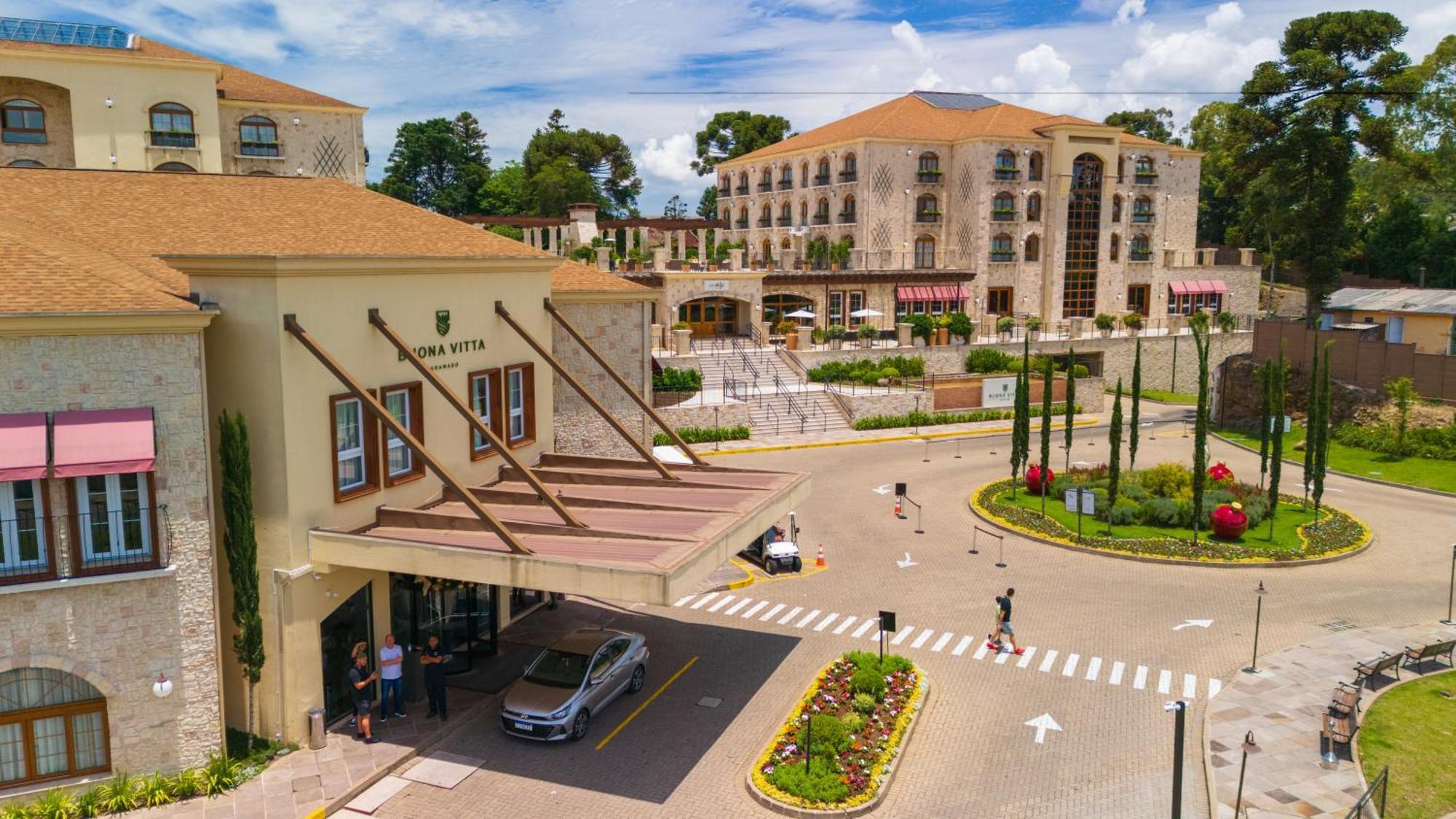 Buona Vitta Gramado Resort & Spa By Gramado Parks Bagian luar foto The photo shows a luxurious hotel or resort entrance, featuring a modern yet elegant architectural design. In the foreground, there is a covered entrance where vehicles are likely dropping off guests. The building has a stone facade and a welcoming e