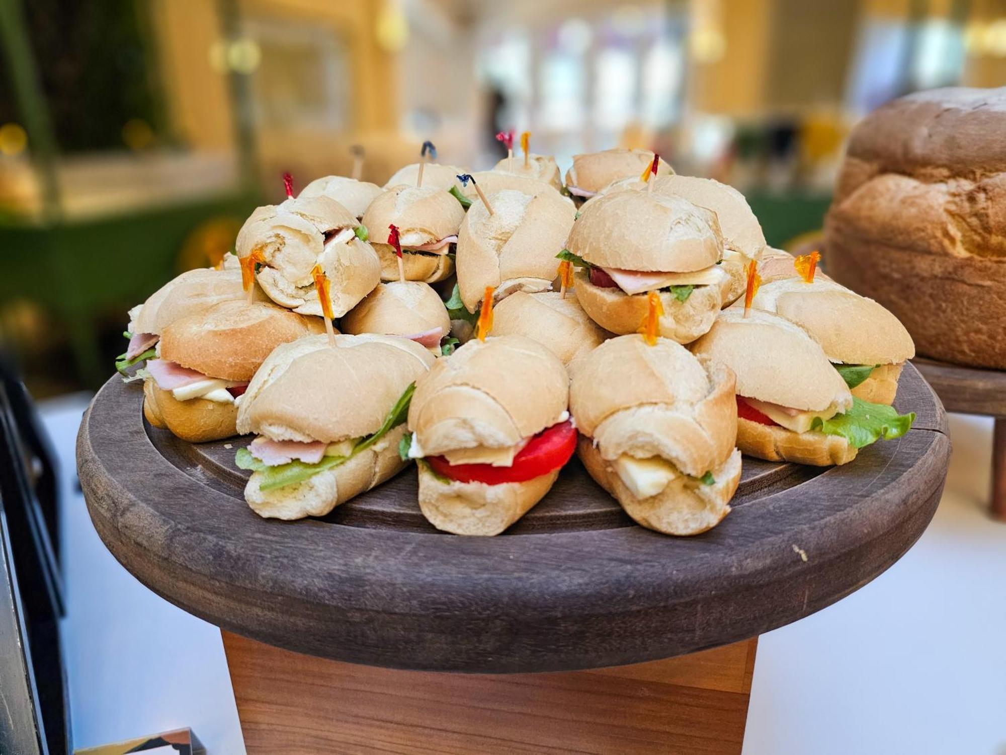 Buona Vitta Gramado Resort & Spa By Gramado Parks Bagian luar foto The photo shows a platter of small sandwiches, likely sliders, arranged neatly on a wooden serving tray. These sandwiches have various fillings, including what appears to be ham, lettuce, and tomato. They are garnished with colorful toothpicks, and t